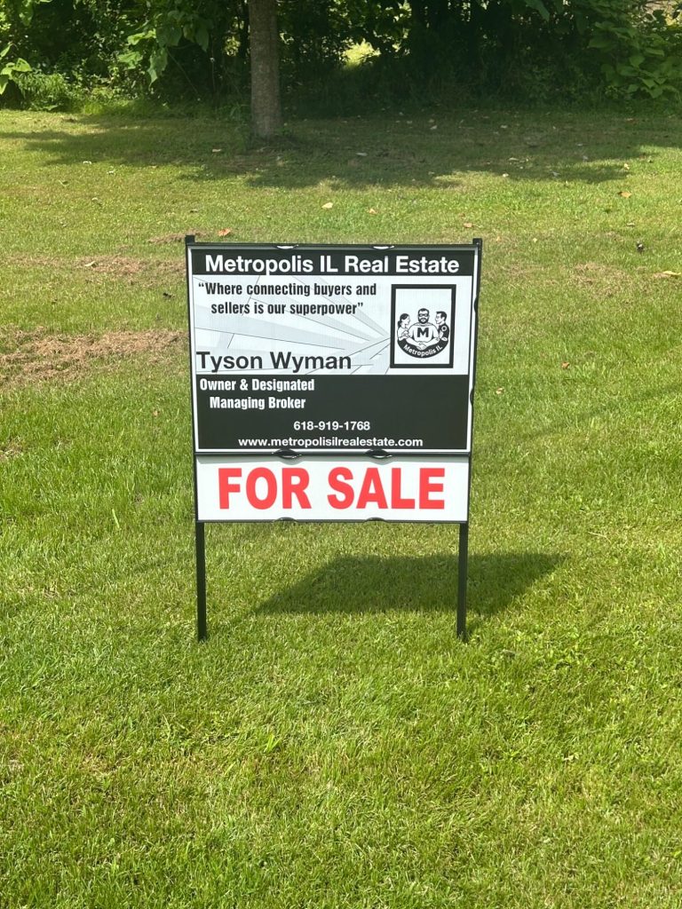 "Metropolis IL Real Estate yard sign- slogan-'Connecting buyers and sellers is our super power' in front of residential home in Metropolis